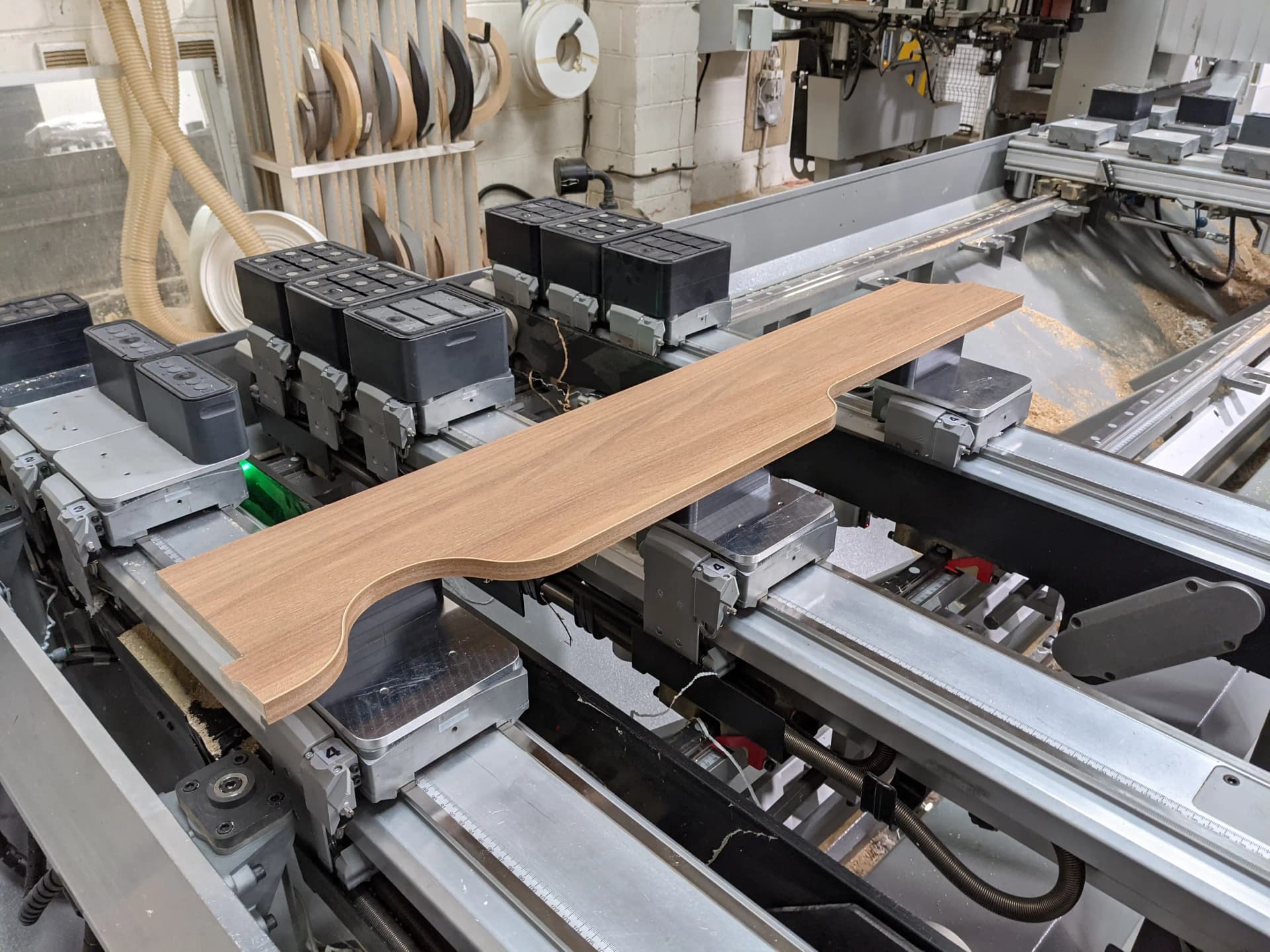 Edge banding machine applying matching tape to an oak-effect board